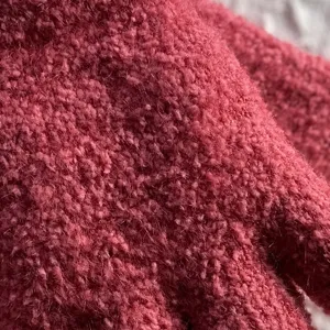 Close up detail shot of the thick warm knitted winter gloves fuzzy fabric texture in pink color.