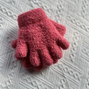 Close-up of thick pink knitted children's gloves, soft textured fabric detail view.