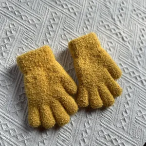 Detailed shot of thick yellow knitted winter gloves, cozy texture, warm kids wear closeup.