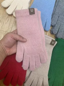 Detailed closeup of colorful women knitted gloves featuring cute bear logo patches and cuffs.