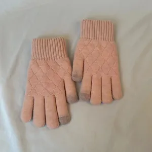 Close up of winter pink knitted gloves with diamond lattice pattern and touch screen fingertips.