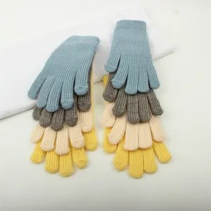 Detailed view showing multi-color stacked knitted winter gloves with warm ribbed cuffs.
