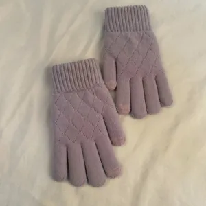 Detail shot of purple knit gloves with diamond pattern and touch screen fingertips.