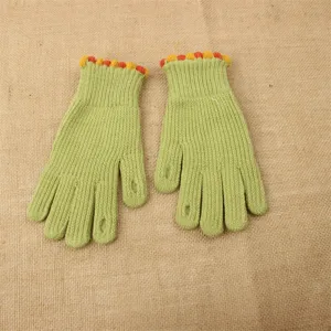Detailed view of winter knitted gloves, cute pom-pom cuffs and fingerless green design.