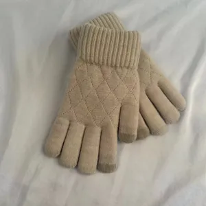 Close-up detail of women winter knit touchscreen gloves with diamond quilted pattern.