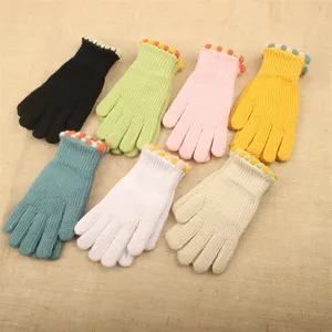 Detailed view of colorful knit gloves with cute pom-pom cuffs, warm winter accessories.