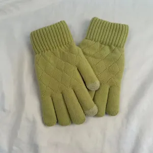 Detail shot of winter warm green knitted gloves with diamond pattern and touchscreen fingertips.