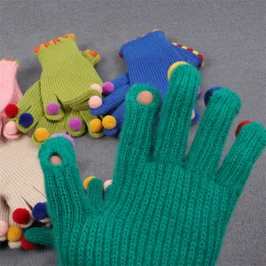 Detailed view of women winter cute knitted fingerless gloves with colorful pom poms warm soft