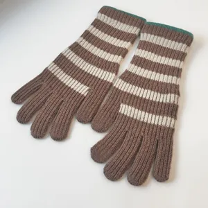 Close-up view of cozy brown and white striped knit gloves featuring a soft green cuff detail.