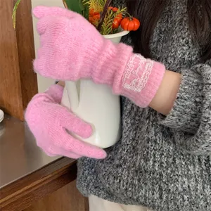 Close up of women pink knit gloves with delicate lace patch detail, cozy winter warmth.
