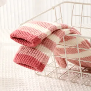Detail shot of pink and white striped knitted fingerless gloves inside a white storage basket.
