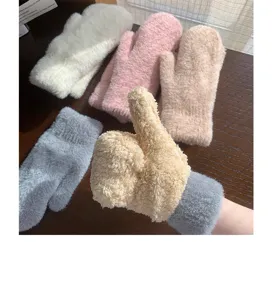 Primo piano di accoglienti guanti invernali in peluche colorati su un tavolo di legno.