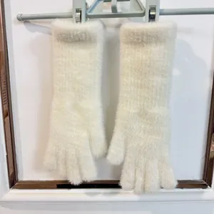 Vue détaillée de gants en tricot pelucheux extra-longs et chauds en blanc avec design ouvert.