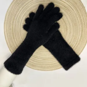 Vue détaillée de longs gants en tricot pelucheux noir, texture douce et chaude d'hiver.