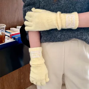 Yellow long knitted split finger gloves with white lace tag, warm winter cold-proof design.