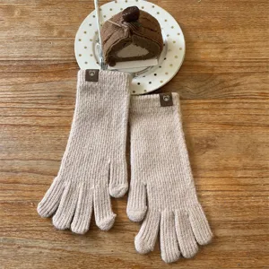 Beige knit winter warm gloves detail view, ribbed texture with cute bear patch accent.