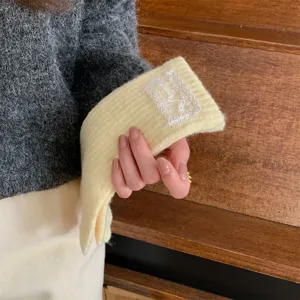 Close-up of winter warm knitted gloves detail, featuring a delicate lace embroidered label.