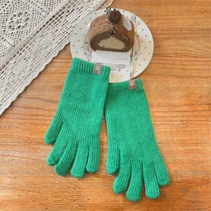 Close-up detail of winter warm knitted green gloves featuring cute bear patch decoration.