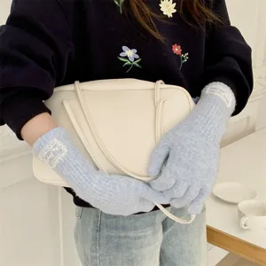 Detailed view of long knit gloves with delicate lace patch, warm wool blend for winter wear.