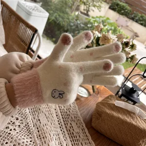 Detailed shot of winter knitted touchscreen gloves with cute rabbit embroidery and plush pink cuffs.