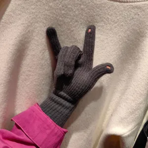 Close-up detail of dark grey winter knit touchscreen gloves with exposed fingertip design.