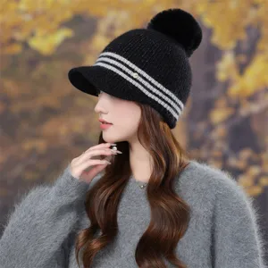 Close-up detail shot of the stylish striped knitted hat with cute pom-pom and metal logo accent.