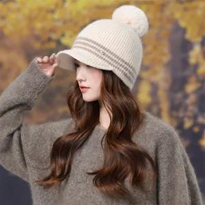Detailed shot of a stylish beige knitted pom-pom hat with brim and stripe pattern for women.