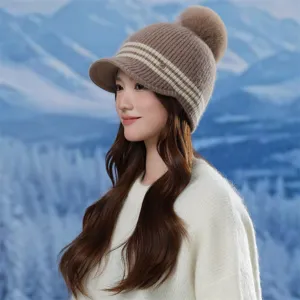 Close-up detail of the stylish winter knitted pom-pom hat worn by a model in snowy scenery.