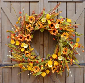 Detailed view of an autumn sunflower wreath hanging on a rustic wooden door.