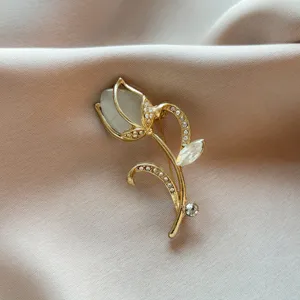 Close-up detail of a vintage gold-toned tulip brooch adorned with shimmering rhinestones and cat-eye stone.