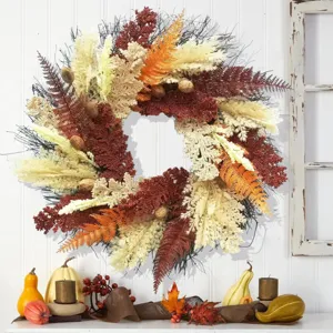 Corona de cosecha de otoño con espigas de trigo falsas y hojas de helecho en pared