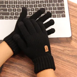 Close-up detail of black knit touch screen gloves, warm winter wear on laptop keyboard.