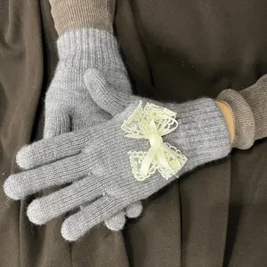 Graue Strickhandschuhe Detailansicht mit süßer beigen Spitzen Schleife und Perle Verzierung.