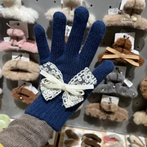 Dunkelblaue Strickhandschuhe mit eleganter weißer Spitzen-Schleife und Perle, Nahansicht.