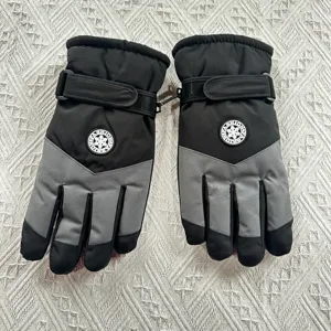 Winter ski gloves detail showing adjustable wrist strap, fleece lining, and waterproof fabric.