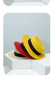 Close-up detail of hand-woven straw boater hats in yellow, red, and khaki with black bands.