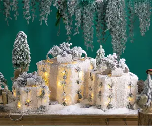 Detailed view of glowing Christmas gift boxes with pine needle and snow decoration