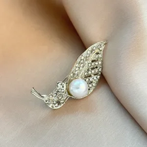 Close-up detail of the elegant leaf-shaped brooch adorned with sparkling rhinestones and a pearl.