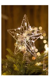 Close-up of a warm glowing LED iron star Christmas tree topper on a tree branch