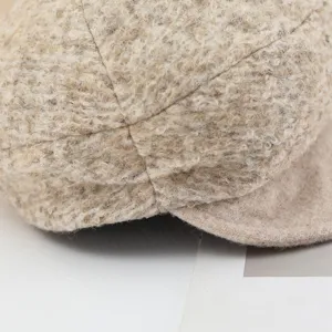 Boucle tweed fabric detail of retro warm newsboy beret hat in soft beige texture close up.