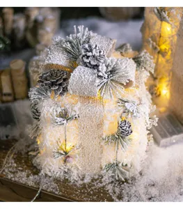 Detailed view of a glowing white Christmas gift box with pine cones and burlap bow