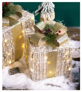 Close-up of lighted Christmas gift boxes decorated with golden bows and snow
