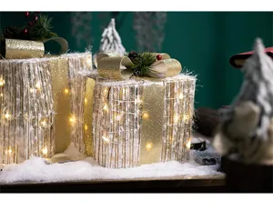 Close-up of glowing Christmas gift boxes with golden ribbons and warm LED lights
