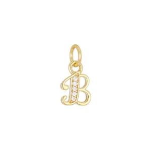 Dettaglio macro di un ciondolo a forma di lettera B placcato oro 18K con pietre brillanti.