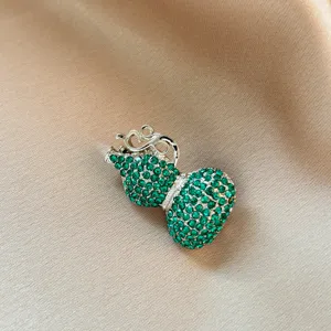 Close-up detail of the elegant green rhinestone gourd brooch, exquisite accessory for outfit.