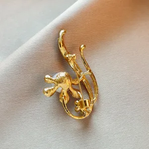 Vue détaillée de l'élégante broche fleur perle dorée, présentant une épingle sécurisée.