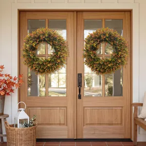 Pair of autumn boxwood wreaths displayed on a double wooden front door for home decor.