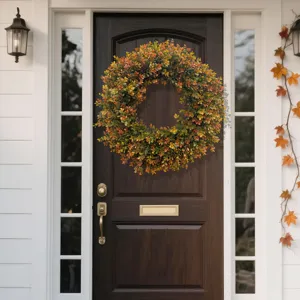 Vibrant autumn faux boxwood wreath displayed on a dark wood front door for home decor