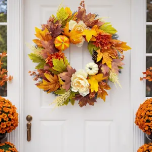 Close-up detail of autumn wreath with colorful maple leaves, white peonies and pumpkins