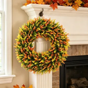 Detailed view of an autumn artificial boxwood wreath hanging on a white mantel.